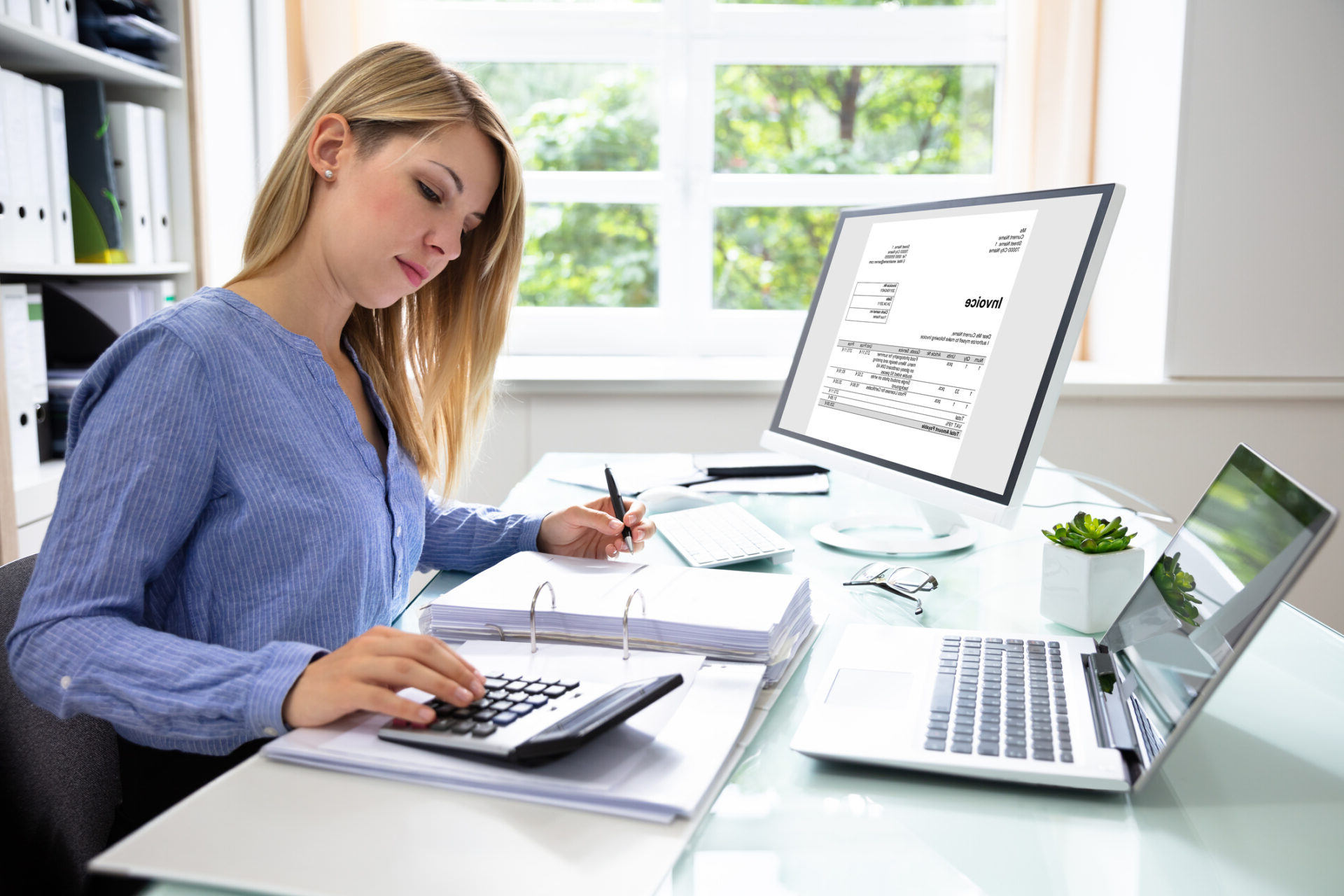 Young Businesswoman Calculating Bill With Computer And Laptop On Desk